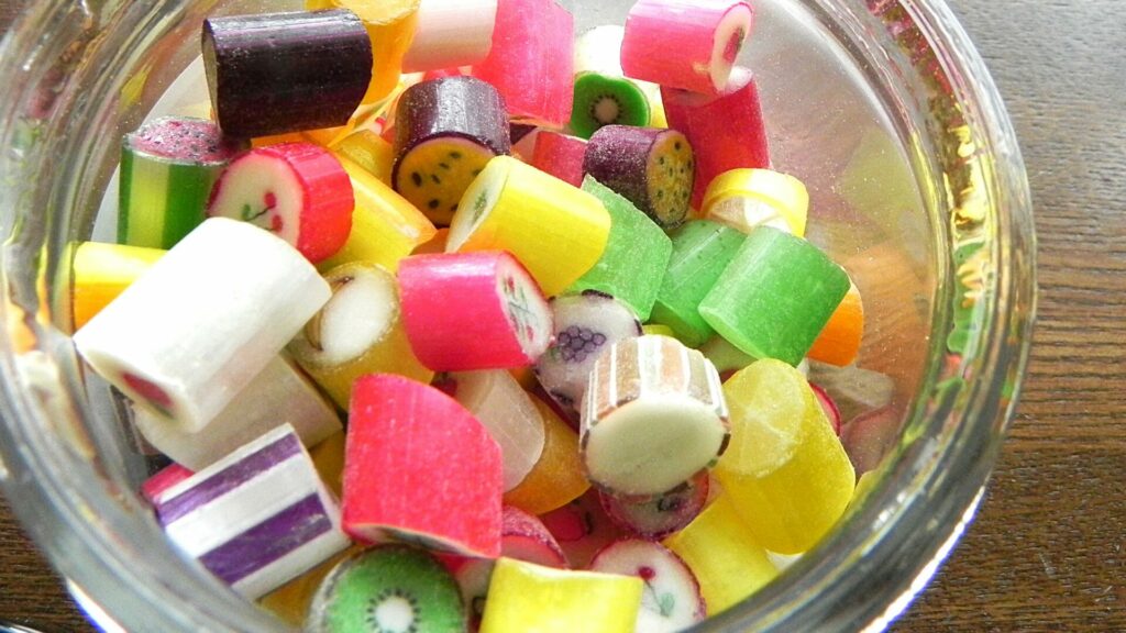 カラフルなキャンディが詰まったガラス瓶。洋菓子のポップな甘さのイメージ。