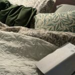 ウィリアム・モリスの寝具に囲まれたベッドで、眠る前に本を読む時間
